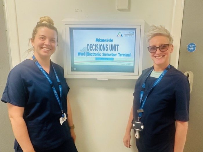 Decisions Unit staff smiling in front of sign